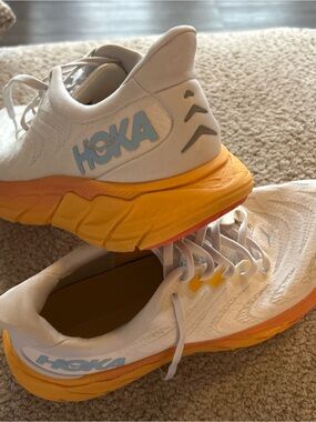 Hoka White Shoes with Yellow-Orange Midsoles and Light Blue Logo